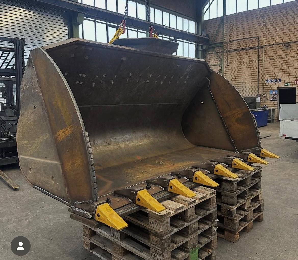 Radlader Schaufel mit gelben Zahnadaptern auf Holzpaletten in der Werkstatt – vor der Reparatur durch IFT Service GmbH